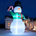 Giant glowing snowman inflatable in a top hat holding a candy cane at night