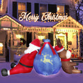 Santa and a reindeer inflatable slumped against a big blue gift sack in front of a lit house