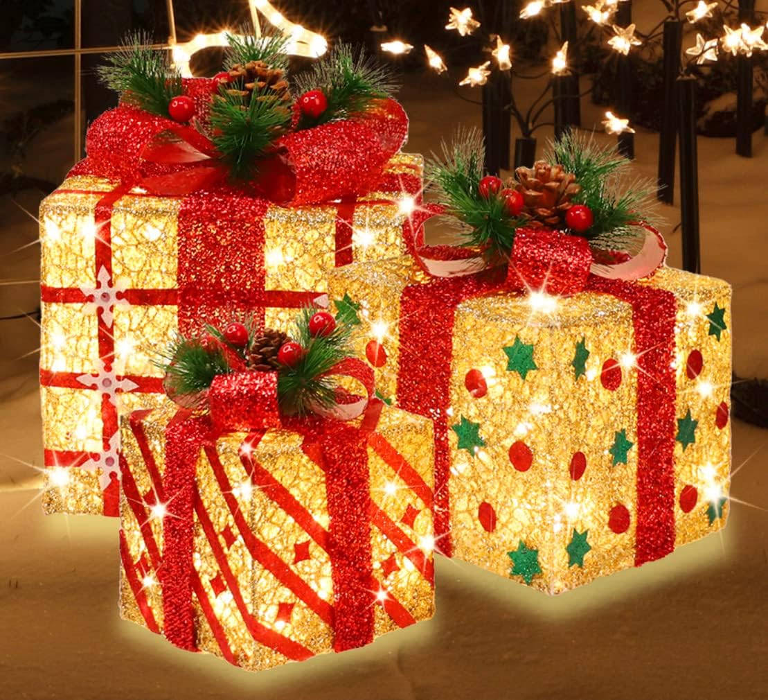Three lighted gold and red glitter Christmas gift boxes with pine and berries on top