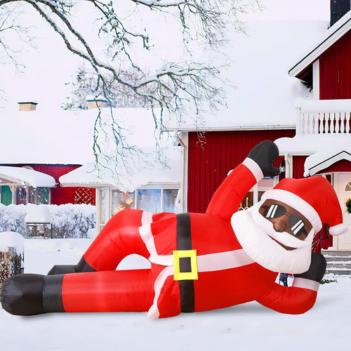 Black Santa inflatable in sunglasses lounging on his side in a snowy yard