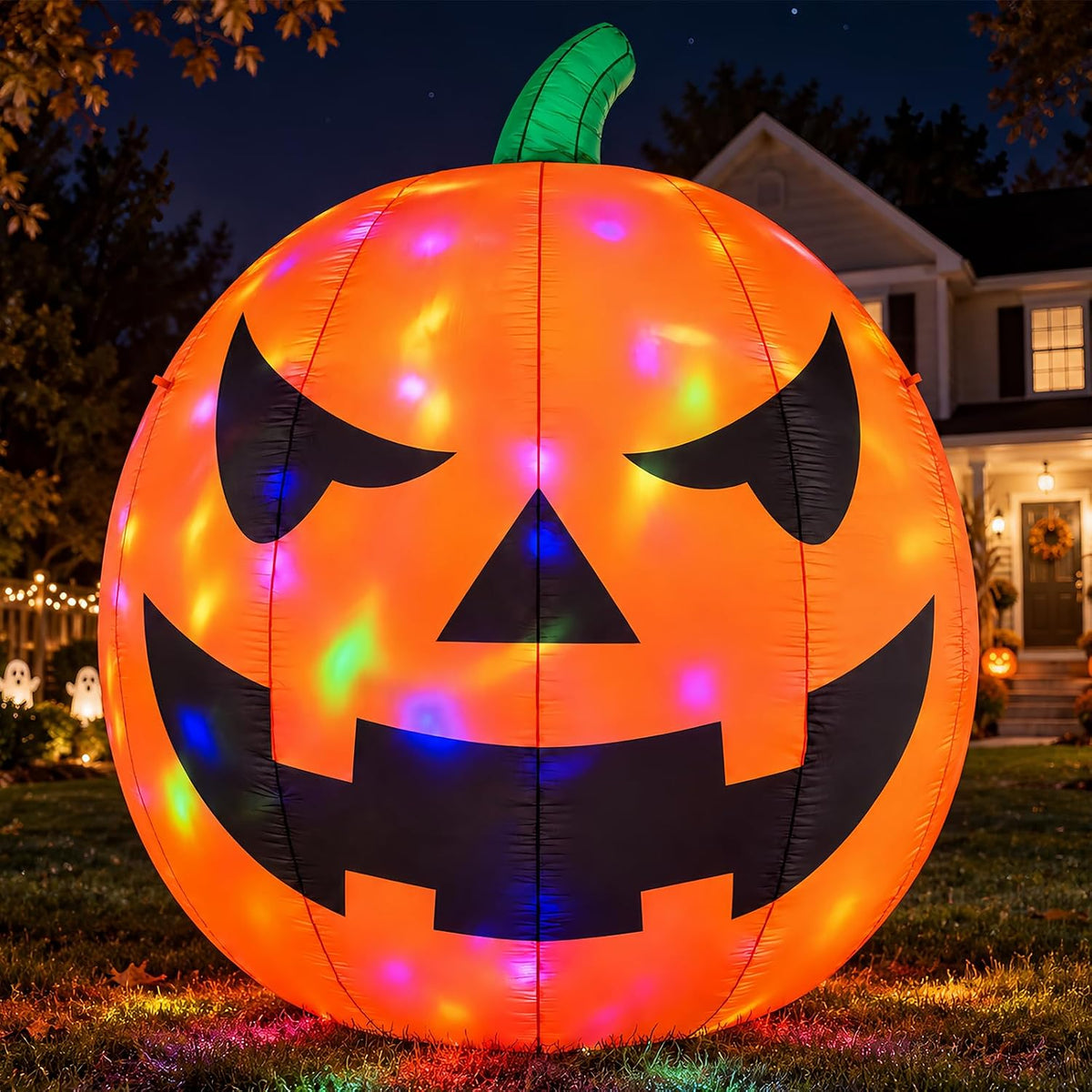 Giant jack-o'-lantern inflatable with colorful rotating light spots on a lawn at night