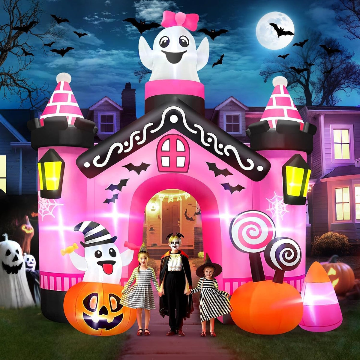 Pink castle Halloween arch inflatable with a ghost on top and candy decorations, kids in costume walking through