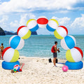 Arch of multicolor beach ball inflatables on blue bases set up on a sandy beach