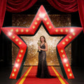 Red star-shaped inflatable arch with marquee lights over a red carpet with a woman holding a trophy