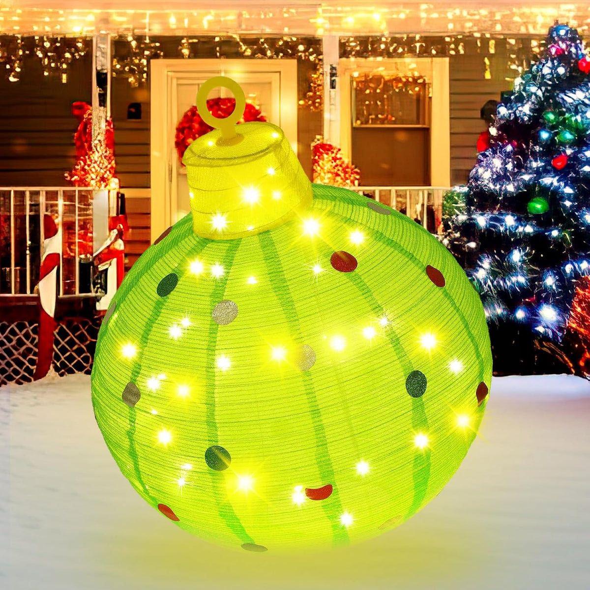Large lighted green glitter Christmas ball ornament on a snowy porch