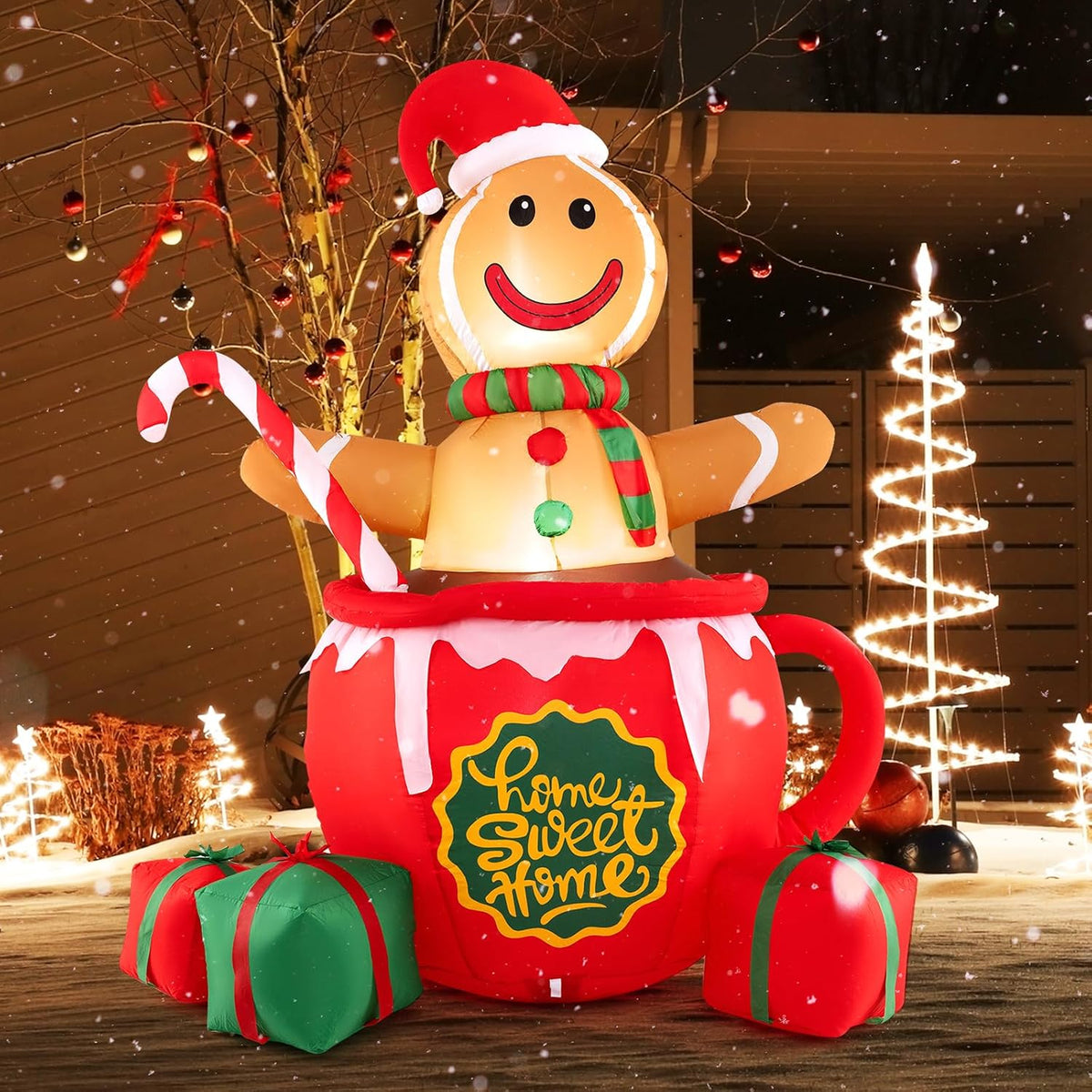 Gingerbread man in a Santa hat in a red Home Sweet Home mug inflatable with gifts at night