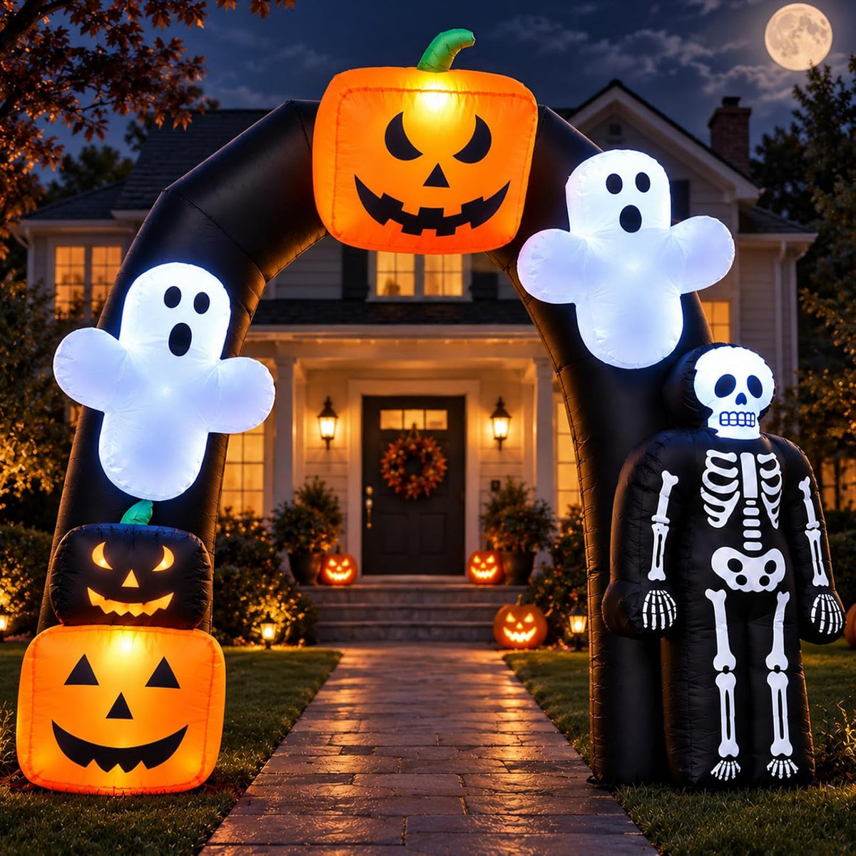 Black Halloween arch inflatable with pumpkins, ghosts and a skeleton over a front path at night