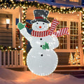 Glittering lighted snowman with a black top hat and red striped scarf in front of a porch